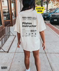 a woman standing on the sidewalk wearing a shirt that says pilates instructor