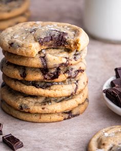 chocolate chip cookies stacked on top of each other next to a bowl of chocolate chips