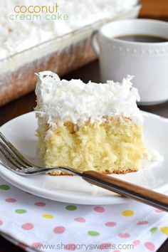 a piece of cake on a plate with a fork and cup of coffee in the background