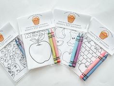 four coloring books with colored crayons on the pages and one has an apple