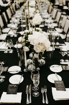 a long table is set with black linens and white flowers in centerpieces