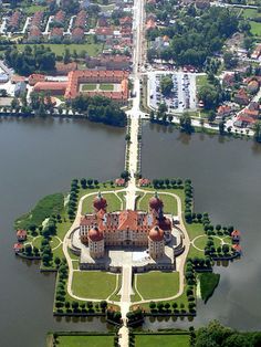 an aerial view of a large building in the middle of a lake with lots of trees around it