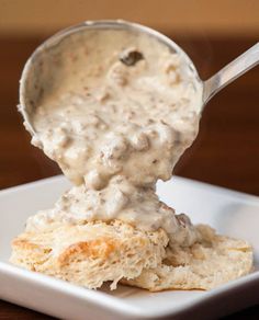 a white plate topped with biscuits covered in gravy and a spoon sticking out of it