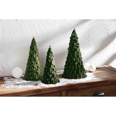 three green christmas trees sitting on top of a wooden table