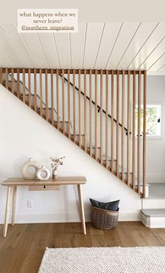 a wooden stair case next to a table with vases on it and a rug underneath