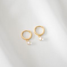 A pair of 14K solid gold 12mm mini hoop earrings accented with a floating, brilliant-cut white Topaz. Comes with gift box.  Earring hoops measure 12mm with a 4mm diameter white Topaz.  Earrings are made of all 14K solid gold and white Topaz. Anti-tarnish, nickel-free, and waterproof.  --------------------♥ PROMOS ♥-------------------- Want 10% off? Join the mailing list by visiting http://bit.ly/vedern . Just leave me a note at checkout if you have any problems applying discount codes. --------------------♥ BUY WITH CONFIDENCE ♥-------------------- Don't love it? Message me to set up a return or exchange. If you find any problems with your items, just send a message with a photo, and a new one will be on its way to you! --------------------------♥ PACKAGING ♥--------------------------- Gol Minimalist Teardrop Huggie Earrings For Anniversary, Yellow Gold Sterling Silver Huggie Earrings With Birthstone, Huggie Earrings With Lever Back For Wedding, Minimalist Huggie Birthstone Earrings, Sterling Silver Huggie Earrings With Birthstone, Anniversary Teardrop Gold-plated Huggie Earrings, Anniversary Teardrop Gold Plated Huggie Earrings, Anniversary Gold Plated Teardrop Huggie Earrings, Minimalist Birthstone Huggie Earrings