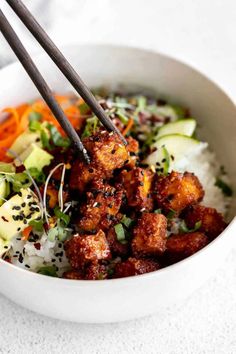 two chopsticks are sticking out of a bowl of food with rice and vegetables