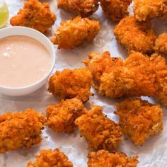 fried food with dipping sauce on white paper next to small bowl and lime wedges