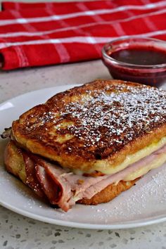 a toasted sandwich with ham and cheese on a plate next to a cup of ketchup