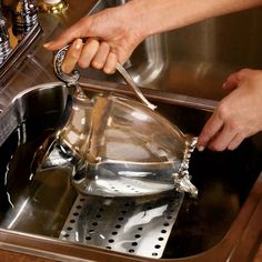 a person is using a strainer to clean a pot in the kitchen sink,