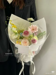 a woman in a suit holding a bouquet of flowers