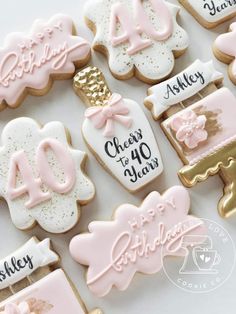 decorated cookies with pink and white icing are arranged on a table for an anniversary celebration