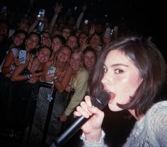 a woman singing into a microphone in front of a crowd