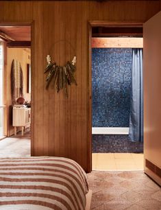 a bedroom with wood paneling and blue glass tiles on the wall, along with a bed