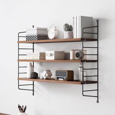 two shelves with books and other items on them against a white wall in an office