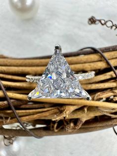 a white diamond ring sitting on top of a wicker basket with pearls and chains around it