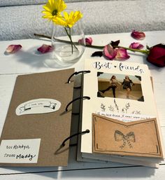 an open book sitting on top of a table next to flowers