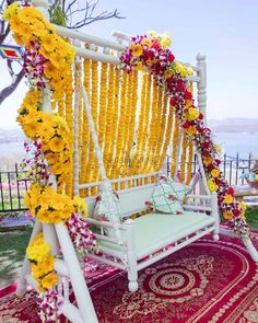 a white swing with yellow flowers on it and a red rug in the foreground