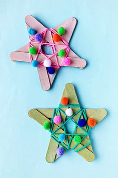 two popsicle ornaments made to look like wooden stars with pom - poms on them