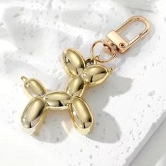 a gold metal keychain with flowers attached to it's side on a white surface