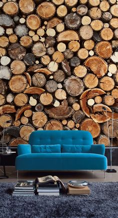 a blue couch sitting in front of a pile of logs on top of a wall