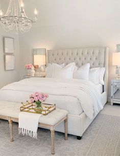 a white bedroom with chandelier and bed