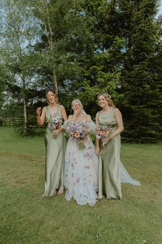 three bridesmaids standing in the grass with their bouquets