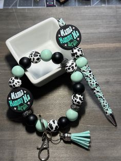 the bracelet is decorated with black, white and mint green beads that have tassels on them