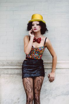 a woman in tights and a hat is talking on her cell phone while leaning against a wall