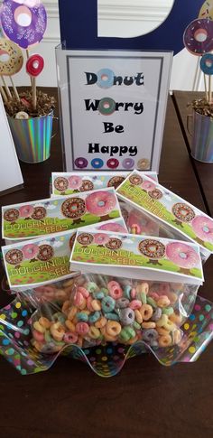 there are donuts in plastic bags on the table with signs and decorations behind them