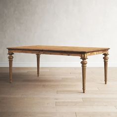 a wooden table sitting on top of a hard wood floor next to a white wall