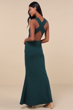 a woman in a long green dress is looking back at the camera and she has her hands on her hips