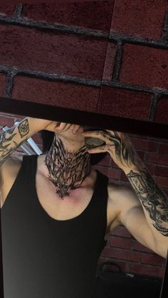 a man with tattoos covering his face in front of a mirror