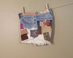 a patchwork jean skirt hanging on a clothes line with pegs attached to it