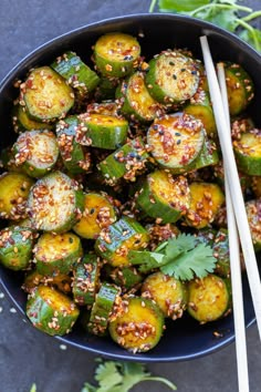 a bowl filled with cooked zucchini and topped with seasoning next to chopsticks