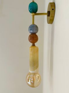 a wall light with three different colored stones hanging from it's arm and on the side