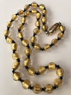 "Gorgeous vintage gold foil bead necklace measuring 23\" long. The beads are 10mm and hand knotted in between with black silk cord. The necklace ends in a gold plated barrel clasp. Lovely piece to wear, great for layering! These are gorgeous beads!" Gold Multi-strand Metal Beaded Necklaces, Vintage Bronze Beaded Brass Necklaces, Vintage Adjustable Hand-strung Beaded Necklaces, Vintage Yellow Gold Polished Bead Necklace, Vintage Gold Hand-strung Beaded Necklaces, Clawdeen Wolf, Cameo Necklace, Silk Cord, Amber Jewelry