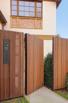 two wooden gates are open in front of a house