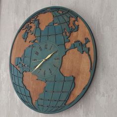 a wooden clock with the world on it's face is hanging on a wall