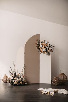 an arch with flowers on the floor next to some candles and napkins in front of it