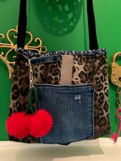 a leopard print purse with red pom - poms hanging from it's front pocket