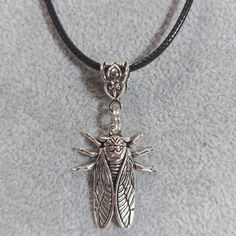 a close up of a necklace with a bug on it