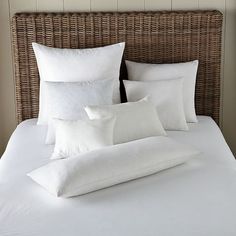 a bed with white sheets and pillows in a room