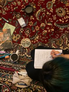 a person sitting on the floor with some books and pens