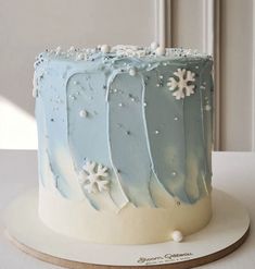 a blue and white frosted cake with snowflakes on it's sides