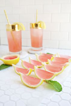 watermelon slices and mint garnish are arranged on a table with gold cups