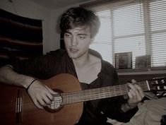 a young man is playing an acoustic guitar