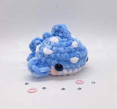 a blue and white crocheted animal with buttons on it's back side