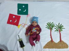 a baby is laying on a blanket next to some crafting supplies and palm trees