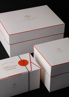 three white boxes with orange trims are stacked on top of each other in front of a black background